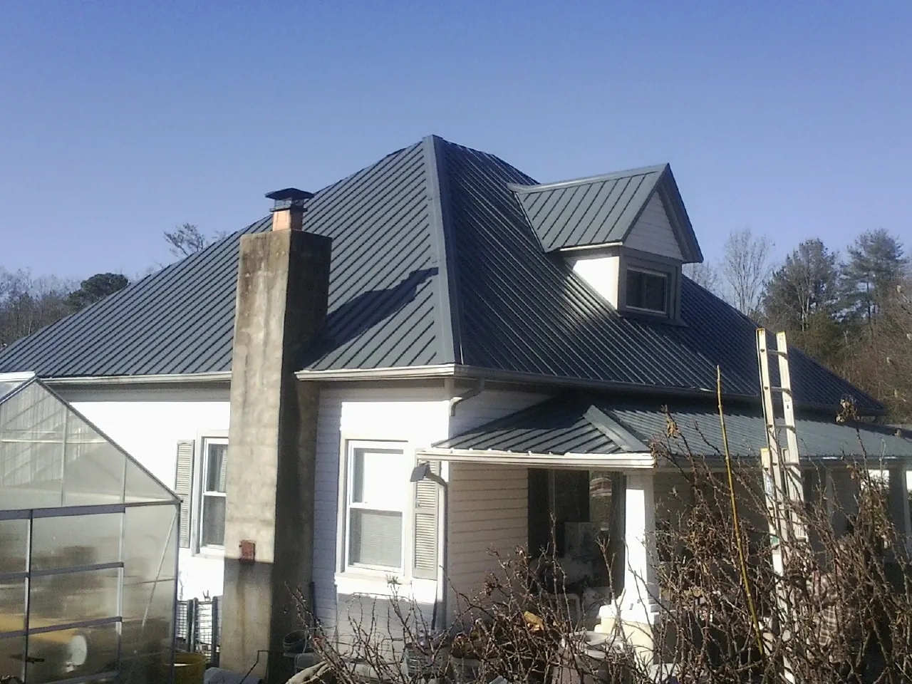 Dark blue standing seam metal roof on a white farmhouse with dormer — Slate & Tile Roof Repair by Roofing Brothers in Wacissa