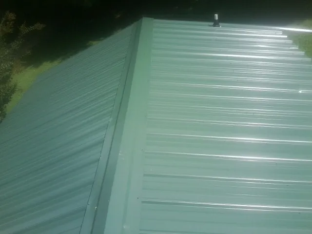 New green metal panels meeting at the ridge of a roof — Flat Roof Repair work by our crew in Wacissa