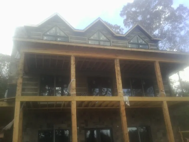 Dormers and porch framing on a large log home under construction — Roof Coating work by our crew in Wacissa