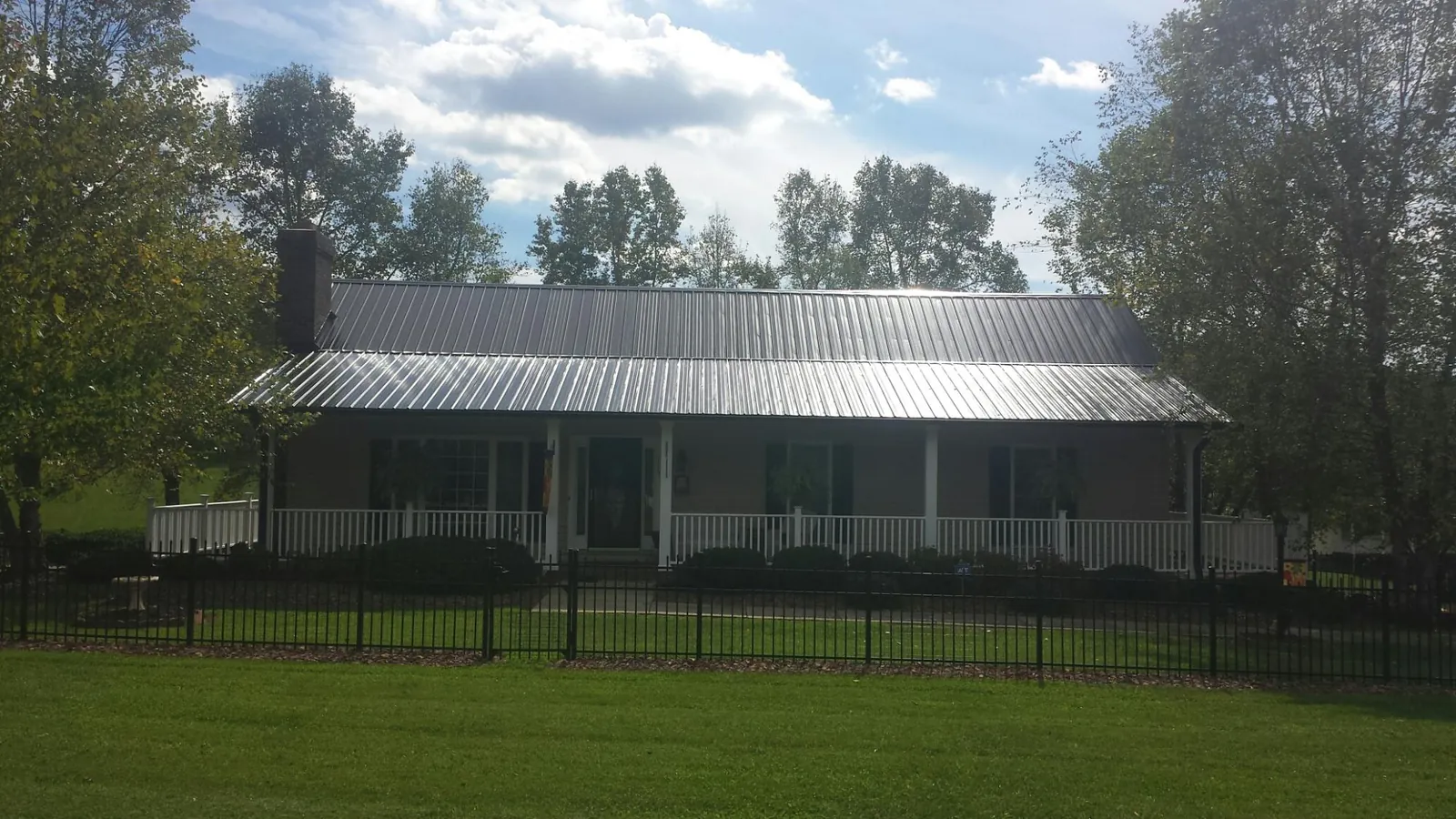 Gray metal roof on a brick ranch with a full width front porch — Gutter Guard Installation work by our crew in Wacissa