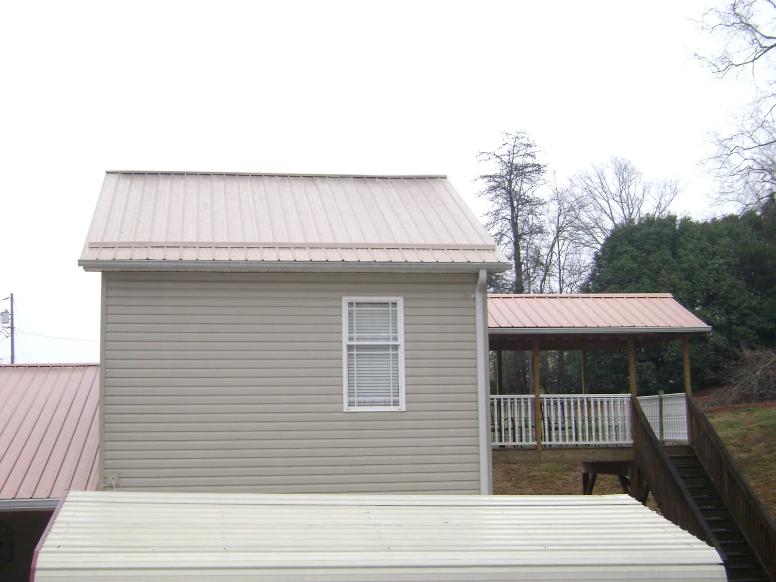 Tan metal roofs on a two story addition and attached porch, from a Roof Replacement job in Wacissa