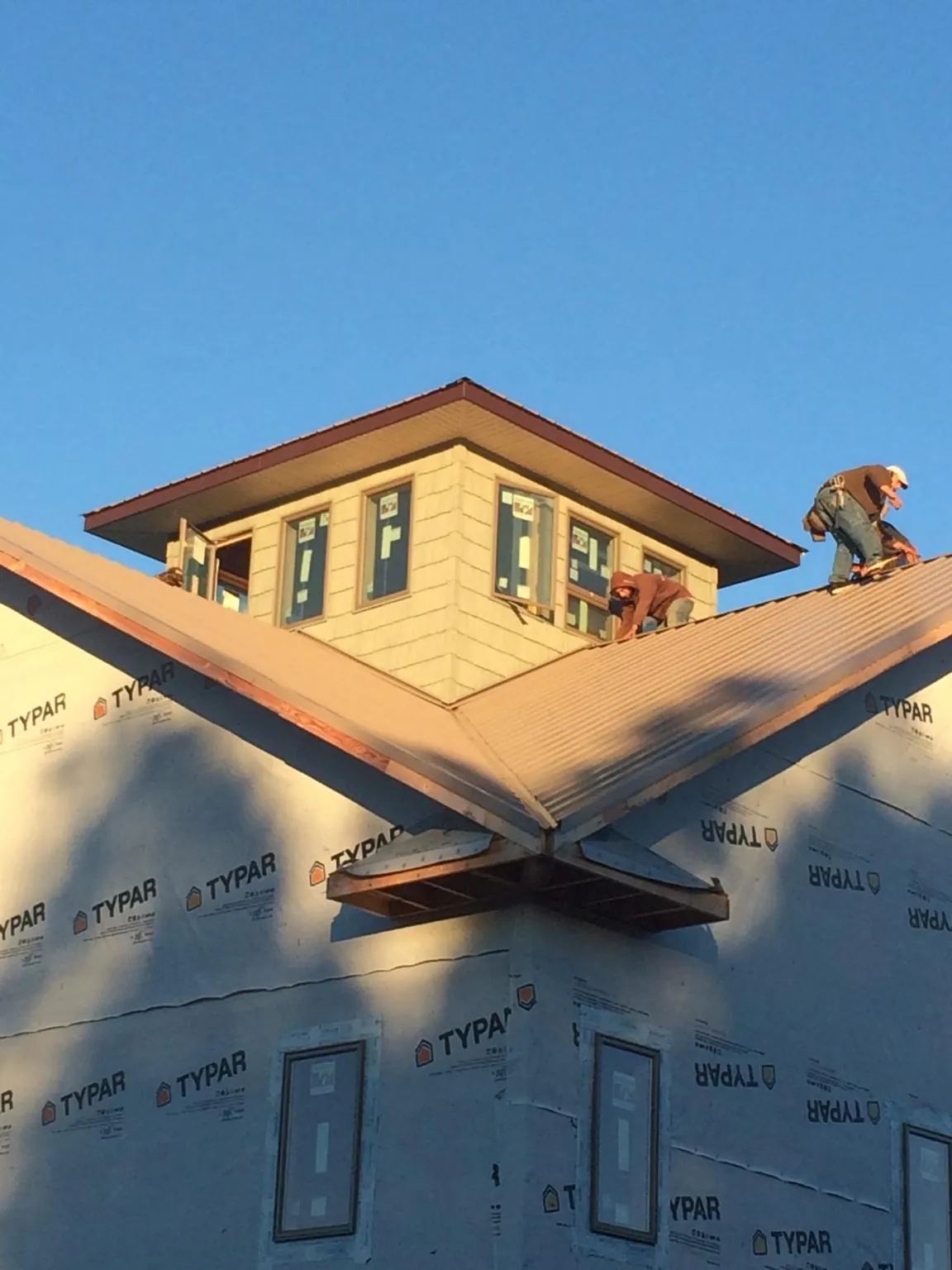 Roofers working around a rooftop cupola on a new metal roof at sunset — Roof Waterproofing in Wacissa by Roofing Brothers